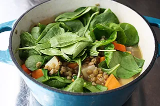 fresh spinach about to be stirred into lentil mixture
