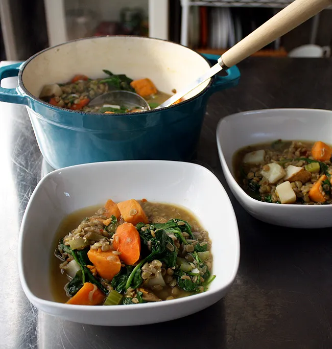 a bowl of lentil stew with spinach and potatoes